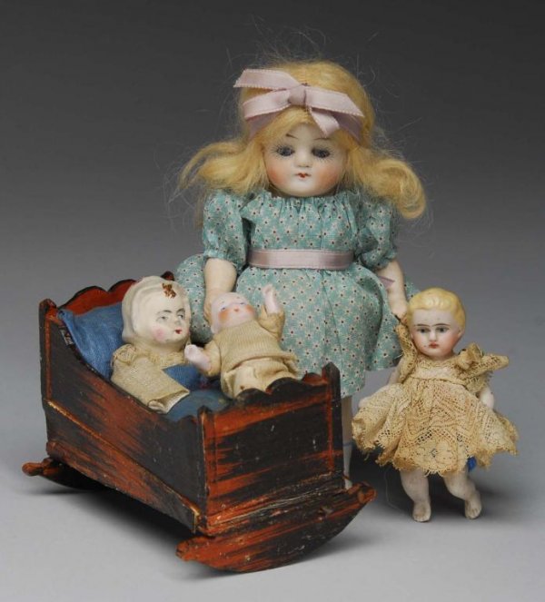 Papier-Mache Squeak Toy and 3 All-Bisque Dolls.: Description Germany, 1870 to 1910. Early papier-mache head and arms baby in a wood cradle squeak toy, all original and wonderful item. 6" chubby all bisque child incised P 607 with glass eyes, origina
