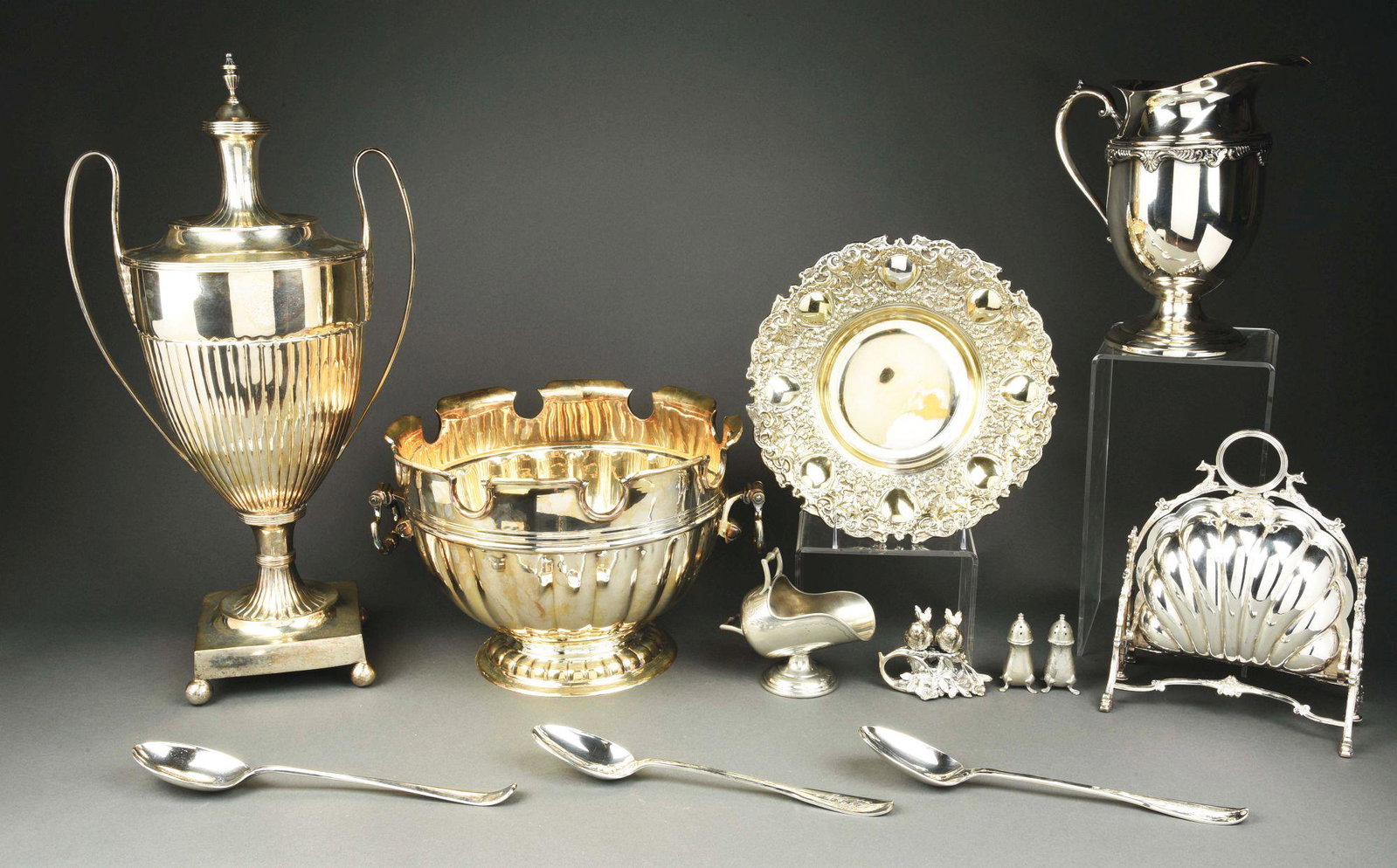 A SILVER PLATED MONTEITH BOWL AND URN.: The bowl of typical early 18thC form, marked underneath Mottahedeh; the Neoclassical style urn with a lobed body and square base and removable spool-form lid; together with other plate including an En