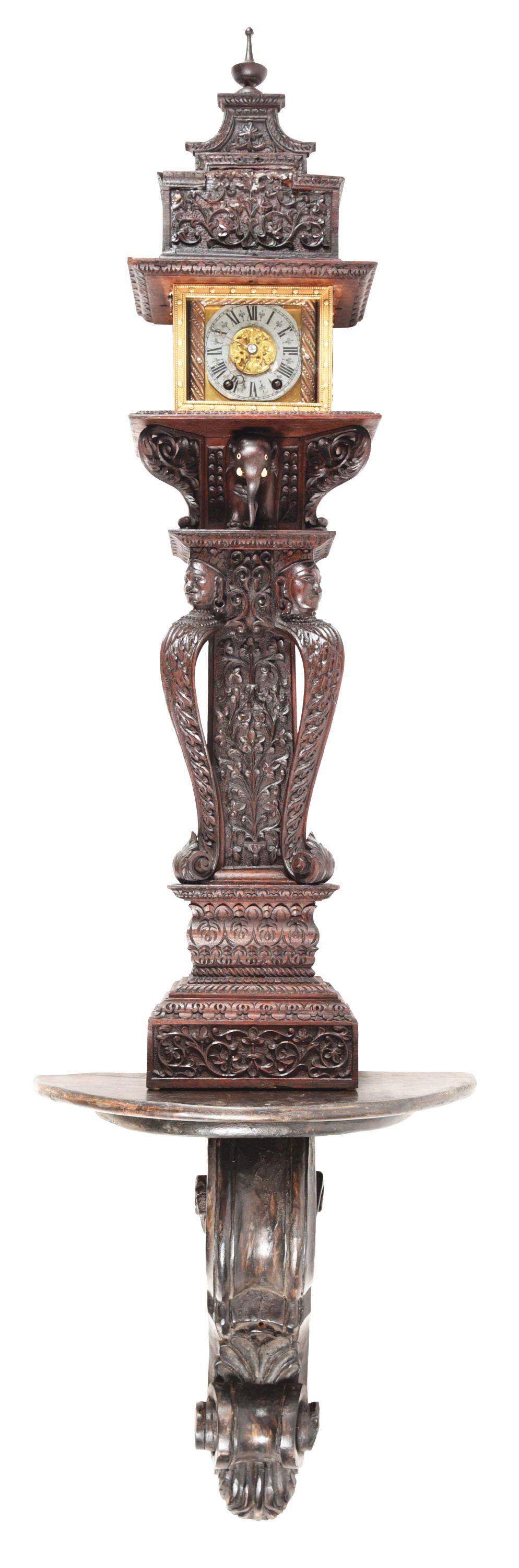 ROSEWOOD INDONESIAN CLOCK WITH SHELF.: Intricately carved hardwood case with figures in waist, below a half figure of an elephant with tusks. The movement and front door by association. Along with a modern clock shelf. This is not a standa