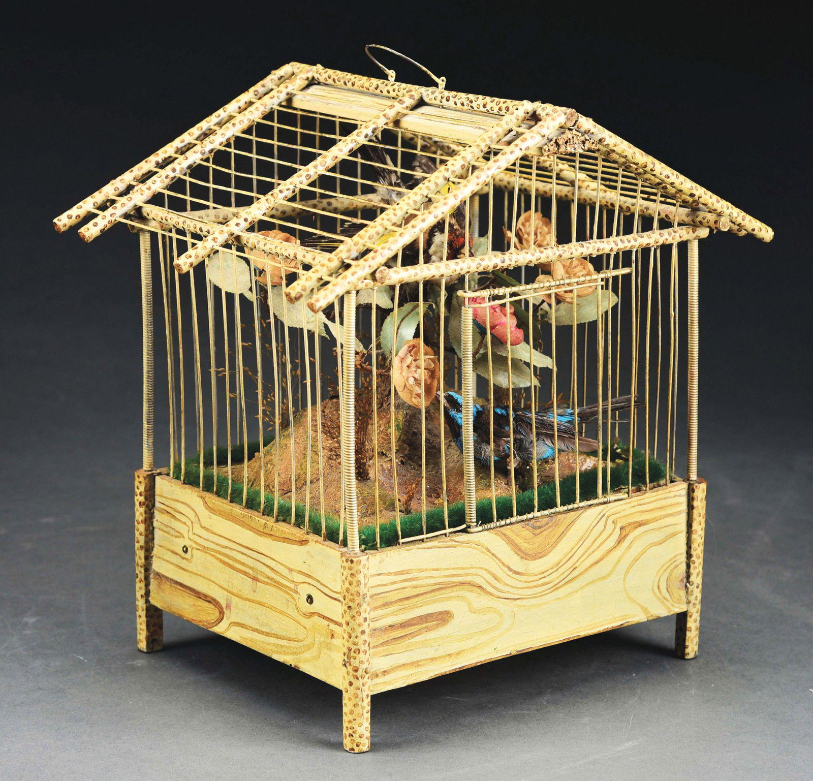 FRENCH AVIARY MUSICAL AUTOMATON.: Grain-painted wooden bird cage, featuring a working music box and two animated taxidermy bird automatons housed in a nature scape. When the music box is played, the birds move, and flap their wings in