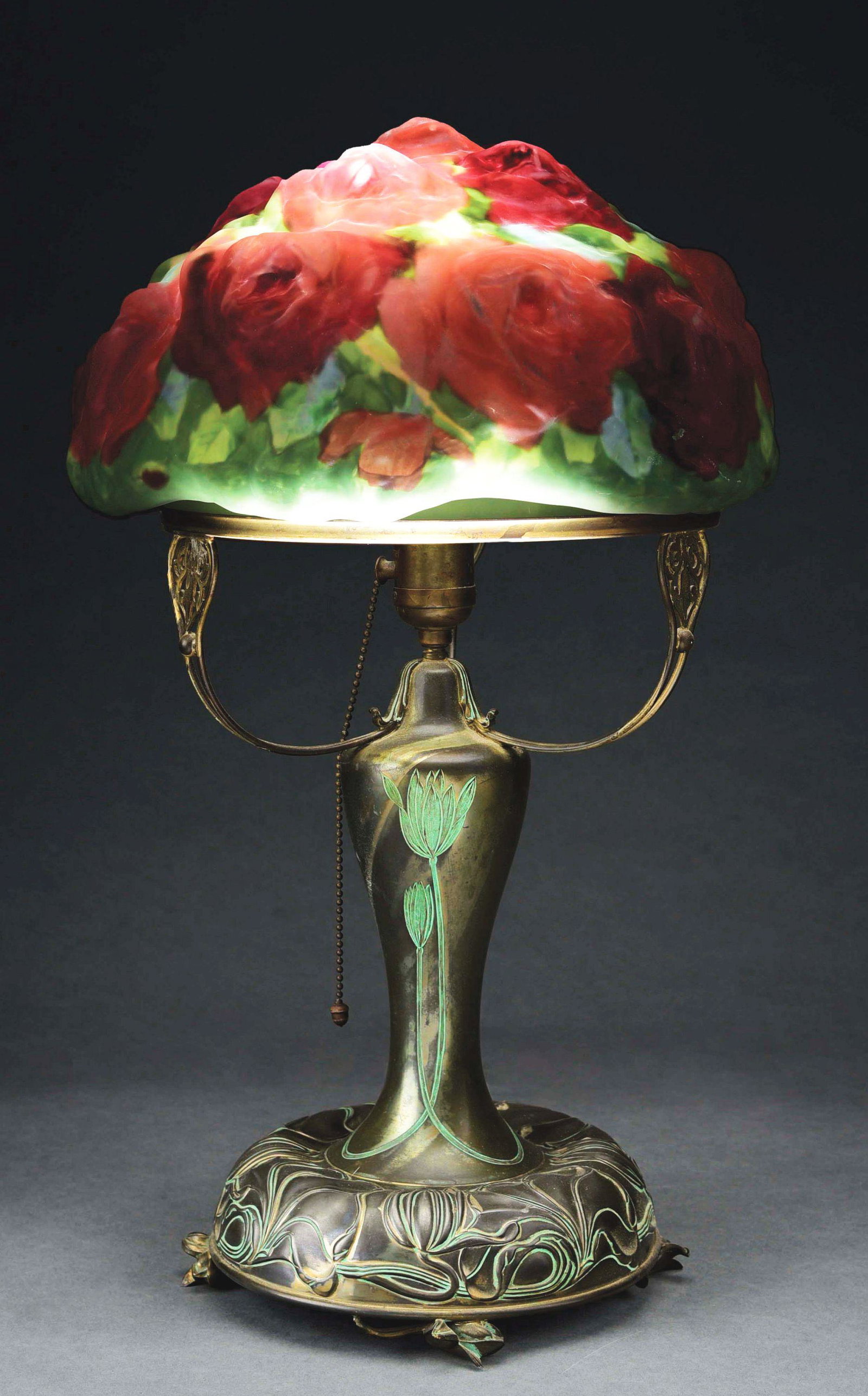PAIRPOINT PUFFY ROSE LAMP.: A beautiful puffy rose lamp by Pairpoint. The shade features a green background with two-tone red roses. The shade measures 13” in diameter and is in excellent condition, with no cracks, or repairs.