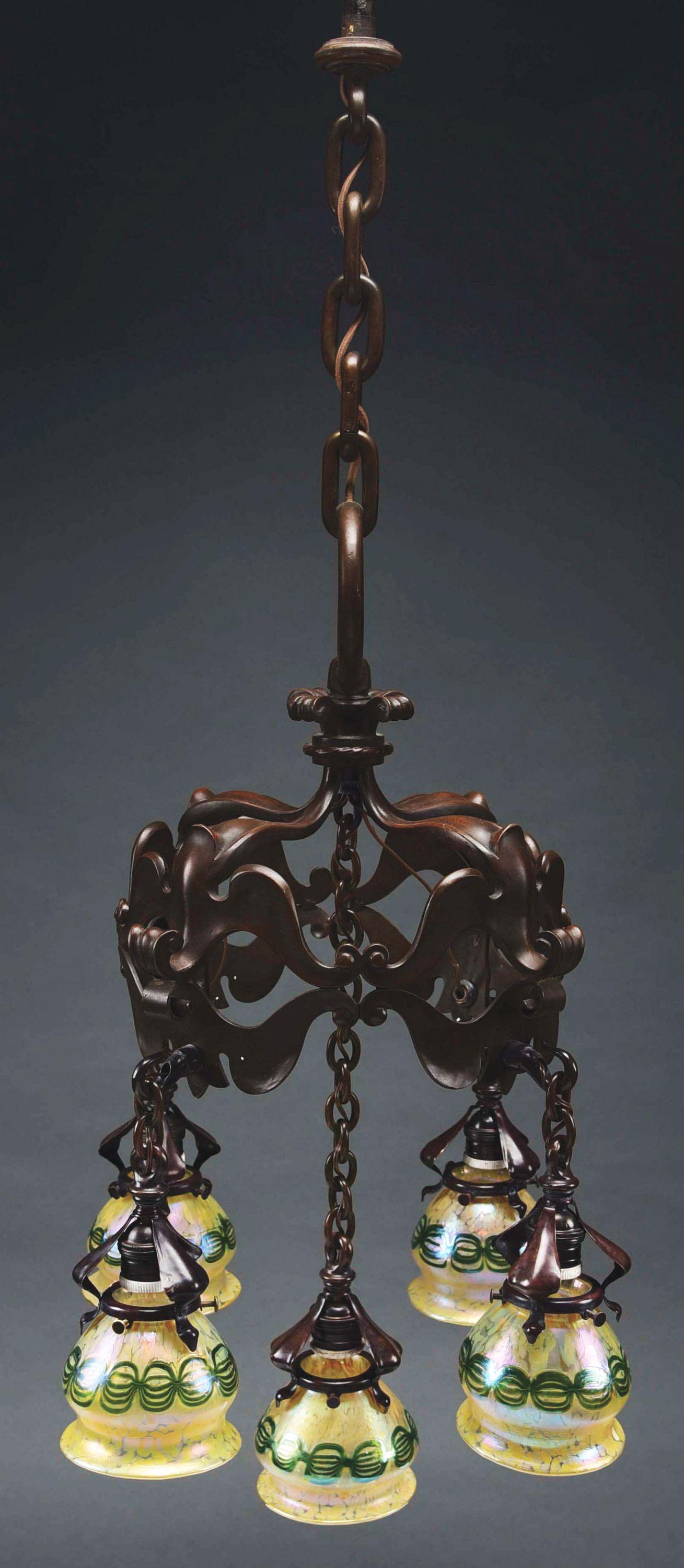 LOETZ CHANDELIER WITH FIVE SHADES.: An Art Nouveau patinated bronze and glass chandelier, decorated with five decorated Austrian art glass Loetz shades, each decorated with iridescent green chain link decoration against an iridescent oi