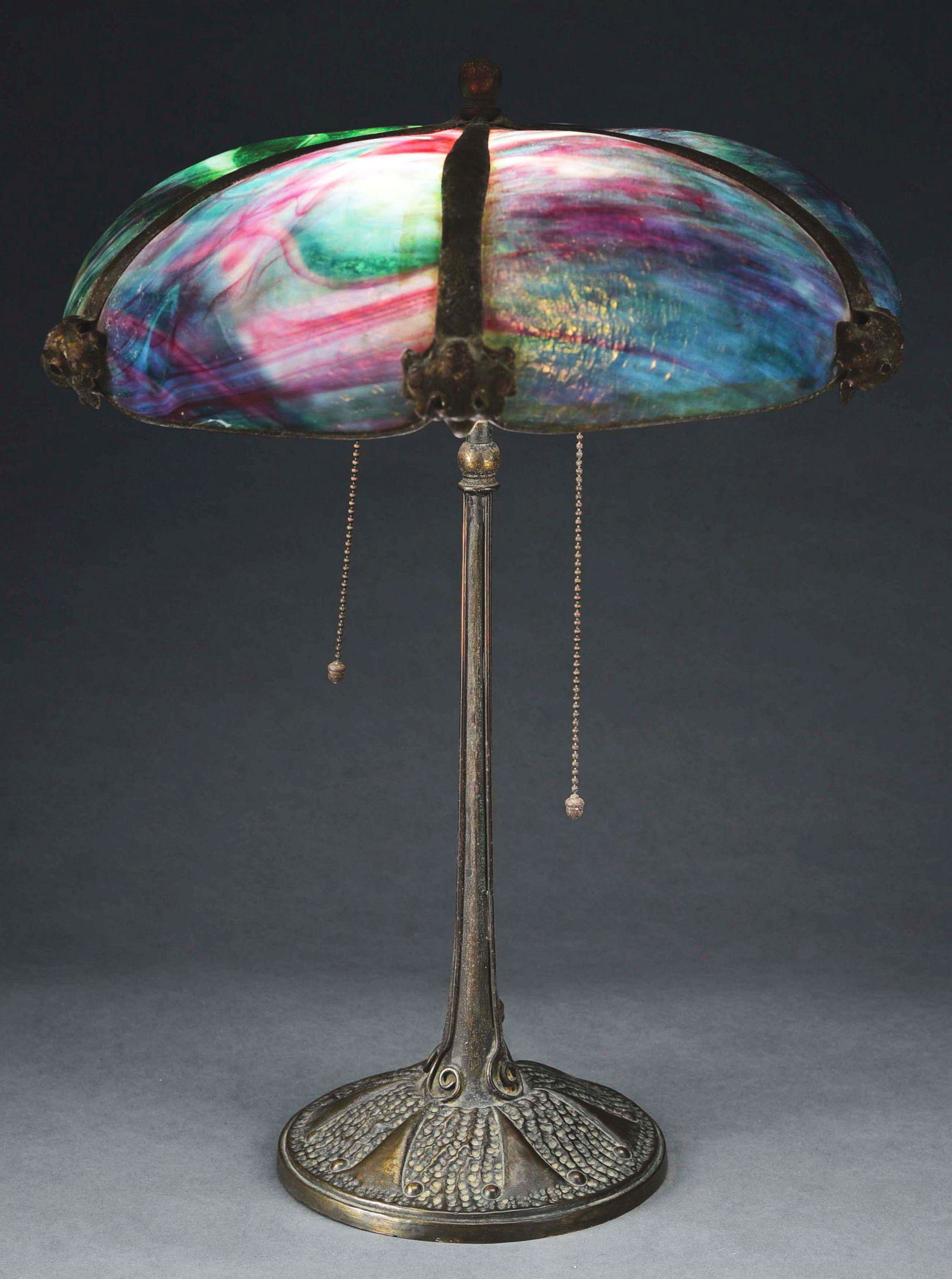 JOHN MORGAN AND SONS SLAG GLASS TABLE LAMP.: A lovely slag glass table lamp by John Morgan and Sons. The slag glass shade features six panels of multicolored glass. The panels are held in place by thick bands of patinated metal, which terminate