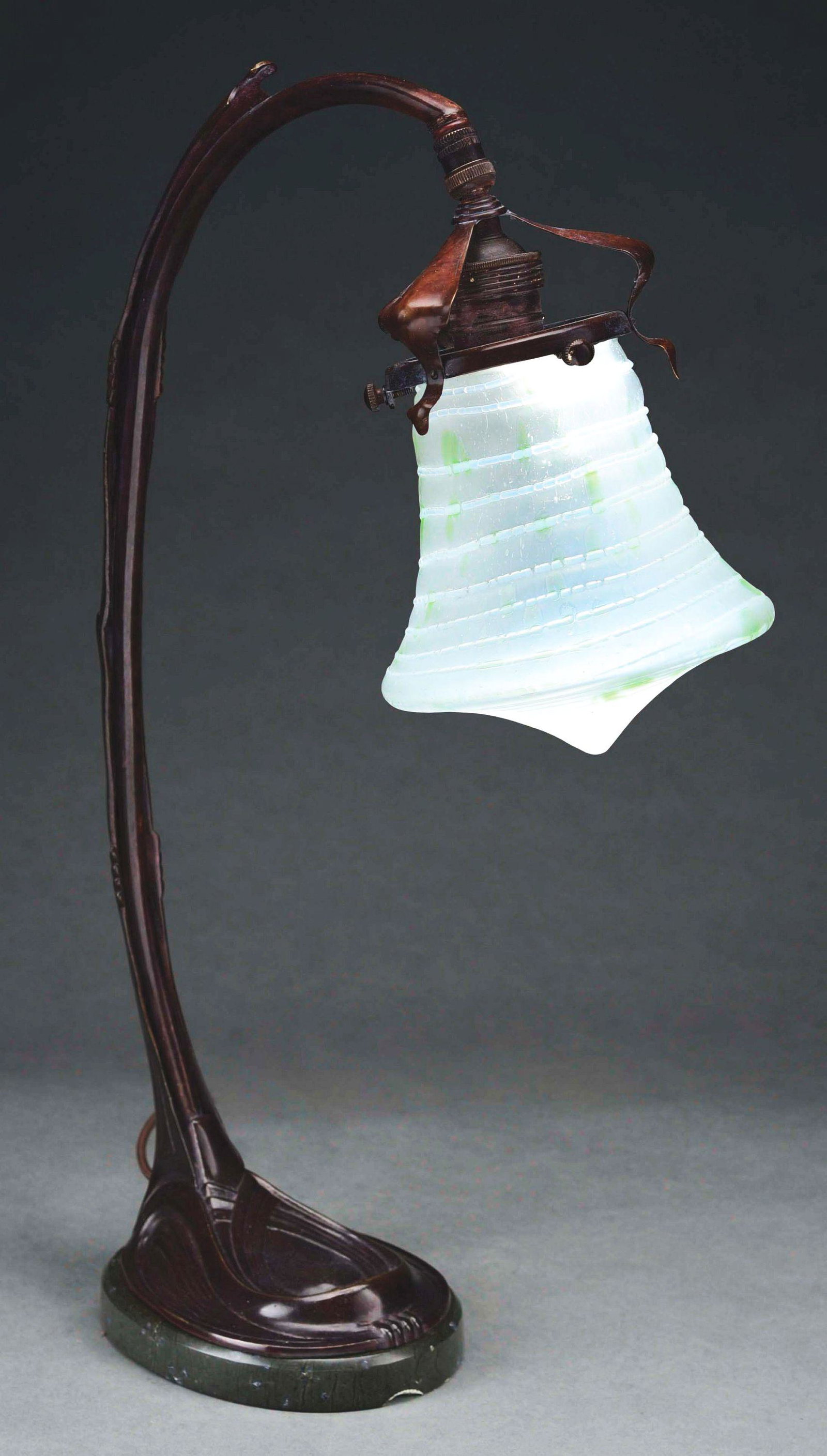 LOETZ ART NOUVEAU GOOSENECK DESK LAMP.: An Austrian Art Nouveau patinated bronze, marble and glass Loetz desk lamp decorated with a etched white glass Loetz shade with green decoration and white line decoration throughout a top a marble and