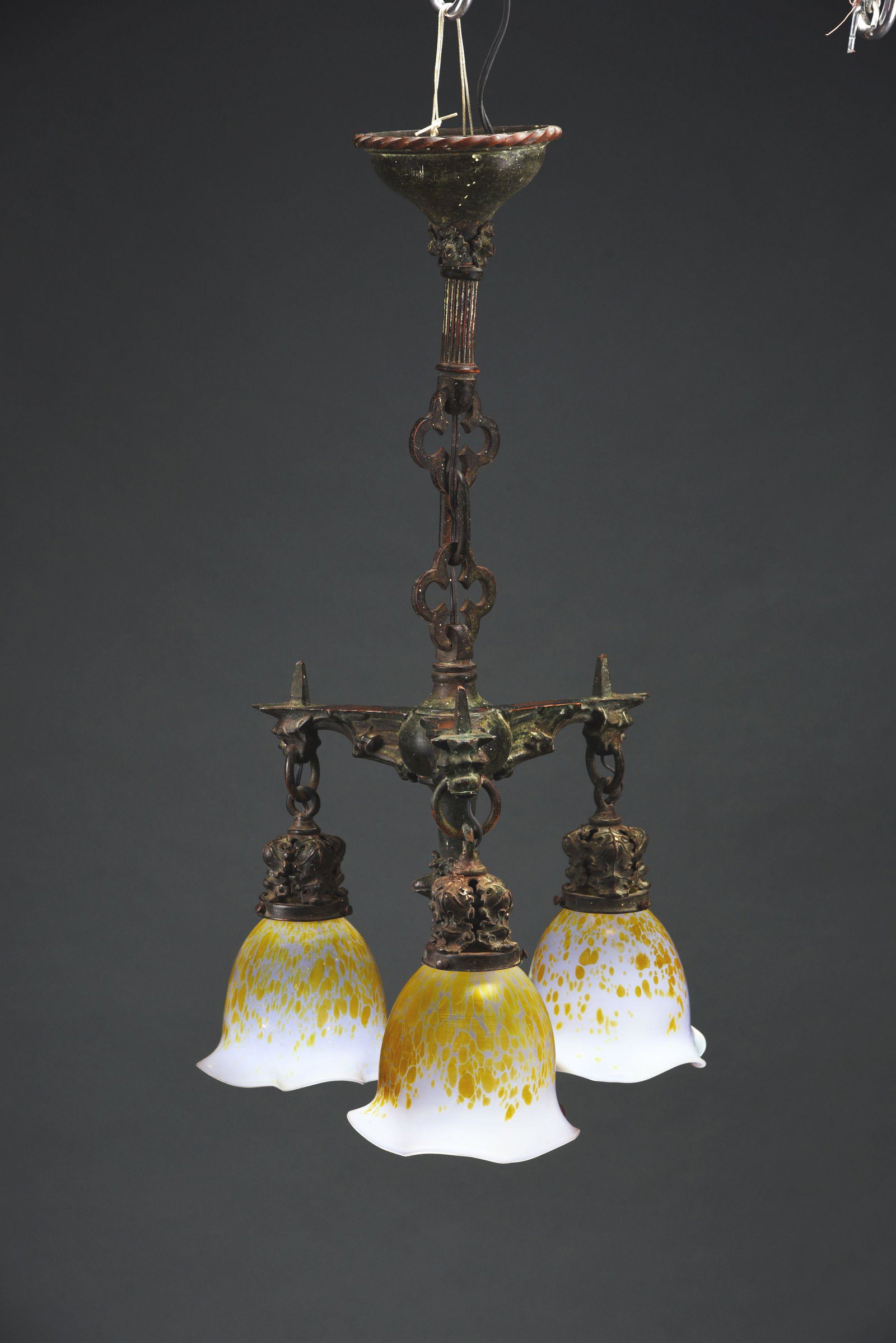 BRONZE GARGOYLE LIGHT FIXTURE WITH LOETZ SHADES.: A lovely, bronze gargoyle hanging light fixture, with 3 Loetz shades. The three shades feature a cream colored background with soft iridescence, with an “oil spot” design with stronger pink and pu