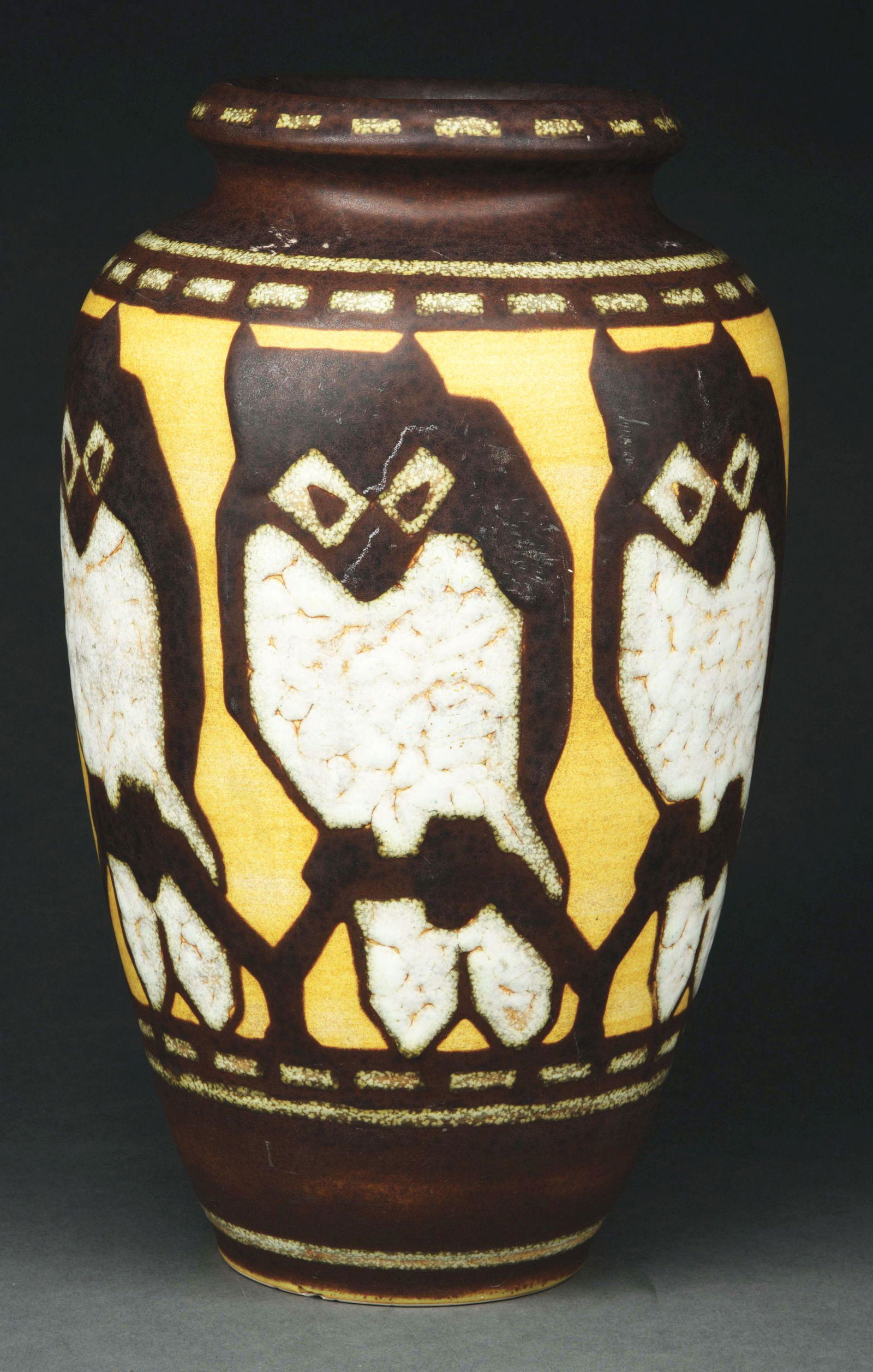 BOCH FRERES OWL VASE BY CHARLES CATTEAU.: A beautiful owl vase by Catteau for Boch Freres. The urn-shaped vase features a yellow and brown background with a large band of owls encircling the vase. Standing 12 - 1/4” tall and in very good co