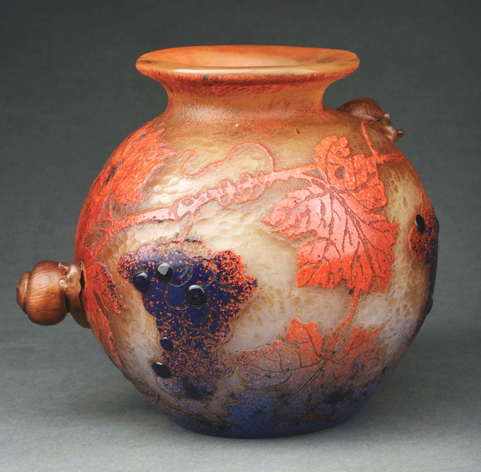 DAUM NANCY SNAIL VASE.: A wonderful cameo and applied snail vase by Daum. The 6 - 3/4” tall vase features a red and orange ground with cameo cut leaves and blue berries. There are two applied snails on the sides of the vas