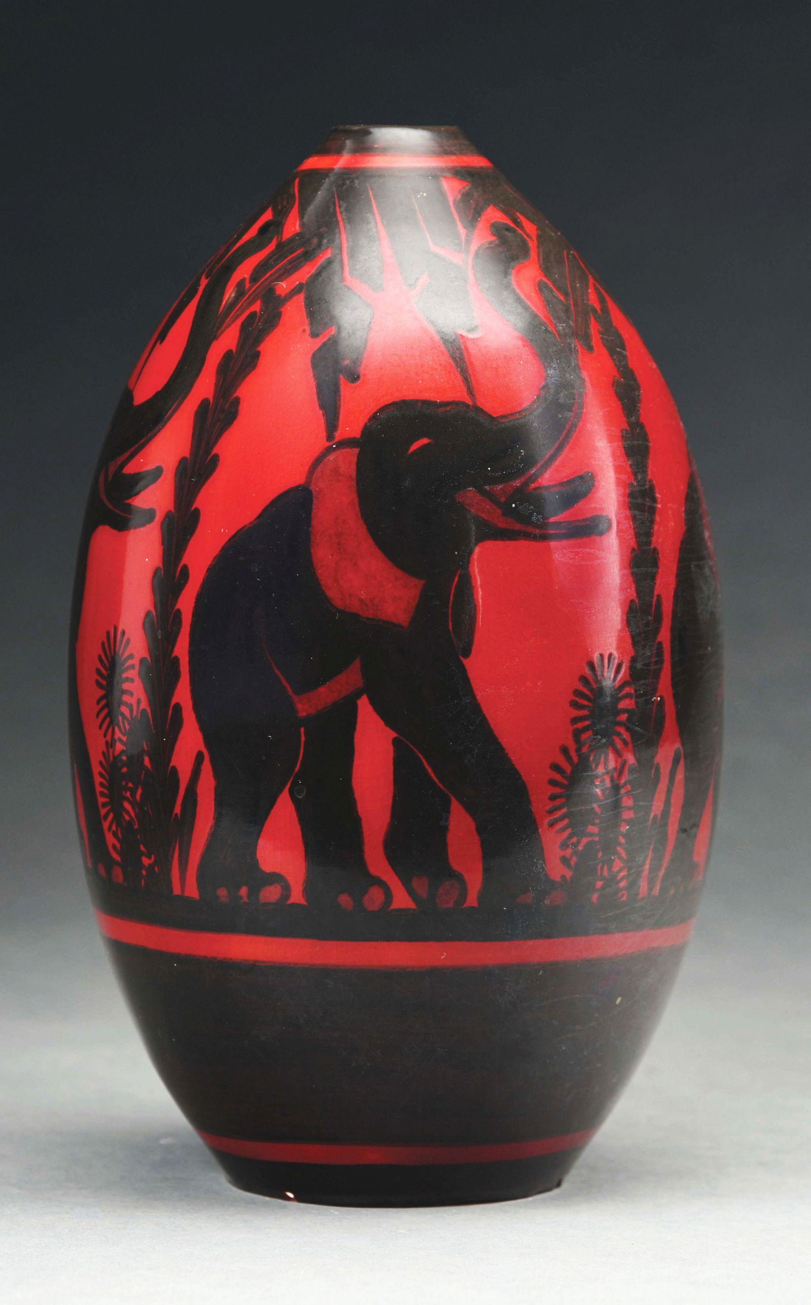 BOCH FRERES ELEPHANT VASE BY CHARLES CATTEAU.: A lovely Boch Freres vase by Charles Catteau. The teardrop-shaped vase features a deep red background with black elephant, lifting up his trunk to feed on overhead branches. The vase is in excellent c