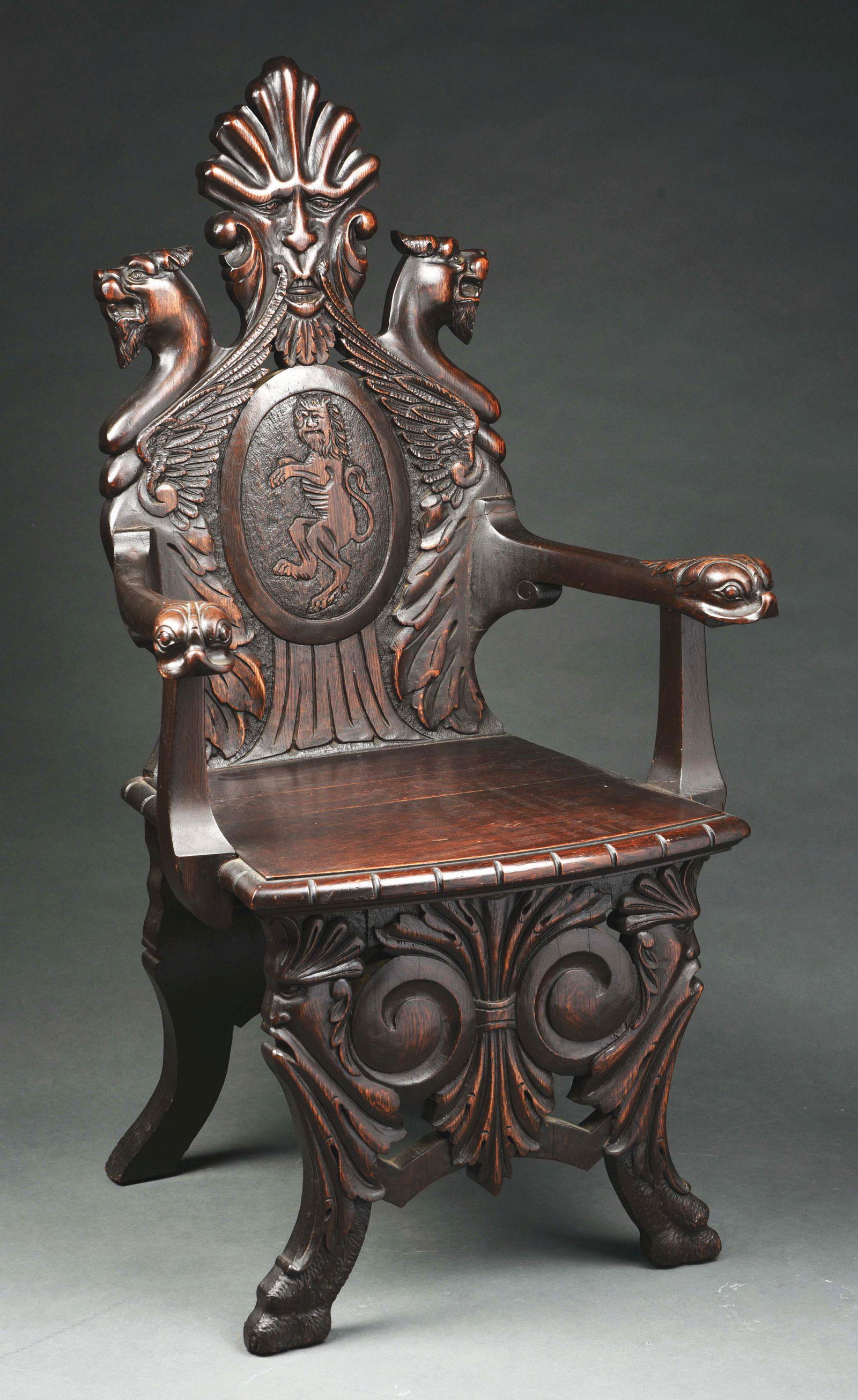 CARVED OAK CHAIR.: Back with a north wind, two griffins and a rampant lion. Arms with carved dolphin heads. Base with two north wind faces. This is not a standard shippable item and will require 3rd party shipping or pi