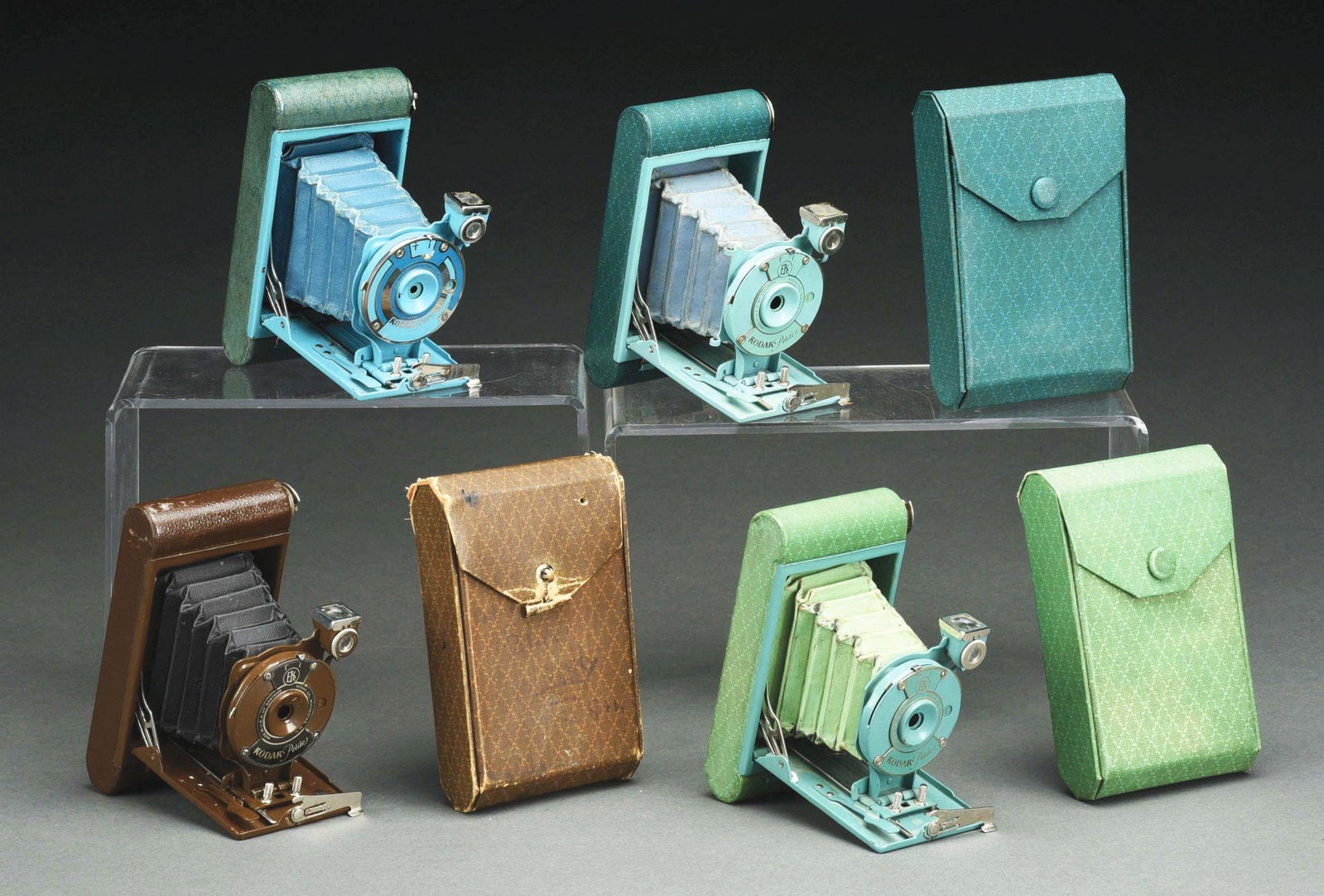 LOT OF 4: KODAK PETITE CAMERAS CIRCA 1929 - 1933.: Kodak Petite Green with case and Art deco front. Exterior in very good condition with minor wear and scuffing. Bellows are intact, but have moderate wear and pinholes. Kodak Petite Teal and grey with 