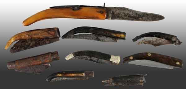 Lot of 9: Primitive Clasp Knives.: One and two blade knives. Eight are handled in horn and one is handled in wood. Includes a two blade clasp knife with high relief bolsters. Front bolster resembles old man winter. Largest: 6" L. (Good