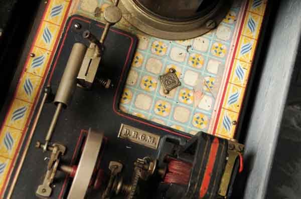 Bing No. 130/511 Vertical Steam Engine.: Includes dynamo and light. Circa 1912. The base is wood covered by a sheet metal lithographed imitation tile. Has a pressure gauge and whistle. The oscillating cylinder drives a dynamo that provides p