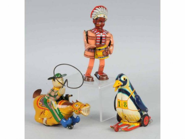 Lot of 3: Tin Figural Toys.: Japanese. Working. Two wind-up and one friction. Includes one cowboy holding a gun with lasso, one Indian beating a drum, and one penguin skiing. Nice lithography throughout with just some scratching.