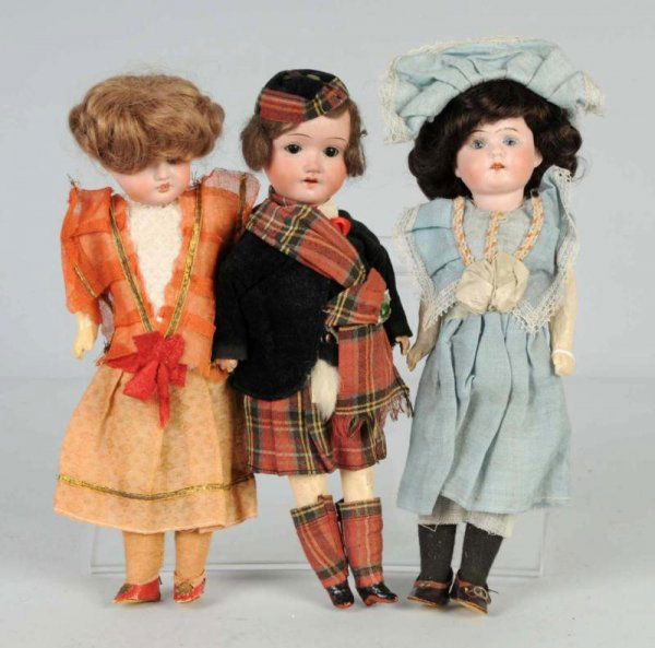 Lot of 3: German Bisque Dolls.: 2 girls with Gebr. Knoch mark, glass eyes, replaced wigs, 5-piece papier-mache bodies with factory original dresses, shoes and socks. With a bisque head boy with sleeping eyes, dressed in factory orig