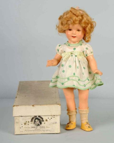 Boxed Ideal Composition Shirley Temple.: Original mohair wig (hair bow missing), lashed sleeping eyes (cloudy), all original in crisp tagged rarely found green print dress, undies, shoes and socks. In original box stamped "Green". Overall cr