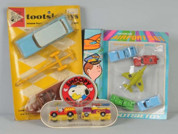 Lot of 3: Die-Cast Vehicle Sets.: Circa 1960s. Includes Tootsie Toy boat and station wagon trailer set, Tootsie Toy airport set, and Snoopy twin fire engine set. All sealed on header cards. Some slight tearing to plastic and bending t