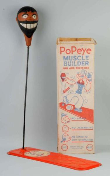 Collette Popeye Muscle Builder Punching Bag.: Includes metal base with nice paper decal of Popeye using muscle builder. Brutus' head is punching bag and has hardened over time. Decal is slightly worn. Includes original box. Size: Base: 28" L.