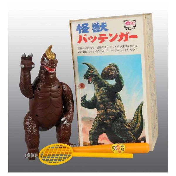 Vinyl Bullmark Godzillla Toy.: Japanese. Circa 1960s. Toy includes figure, tennis racket, wiffle ball bat, ball machine, and five plastic baseballs sealed in package. Includes original box with nice colorful depiction of Godzilla o