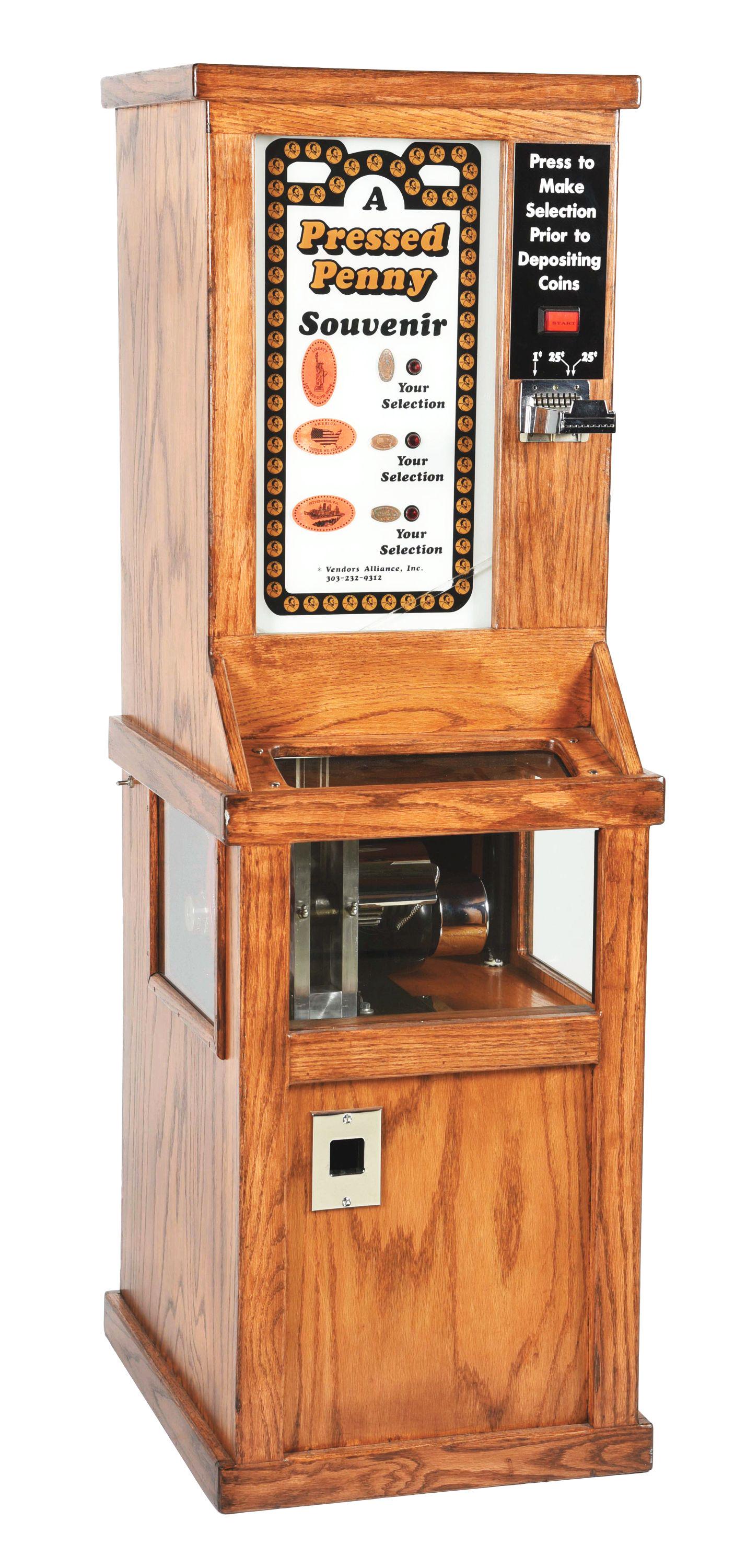 COIN-OPERATED PRESSED PENNY SOUVENIR MACHINE.: This is a fully restored souvenir dispenser for pressed pennies, made by The Vendor's Alliance Company. For two quarters and a penny, the machine will stretch your penny into a statue of liberty souve