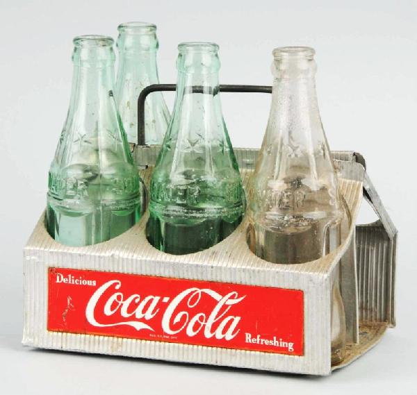 Aluminum Coca-Cola Bottle Carrier with 4 Bottles.: Description 1950s. Contains three flavored bottles and one 1923 Christmas bottle. Medium to heavy wear on the carrier and three of the four bottles. Condition (Good - Very Good). Size Carrier: 6 - 1/2