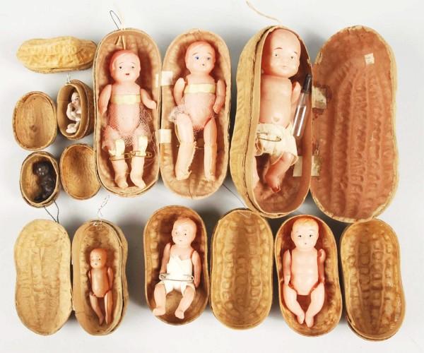 Lot of 12: Peanut Boxes & Footballs.: Six papier mache peanut boxes contain celluloid or bisque babies. One has two dressed babies. Also includes four footballs and one walnut box. Size: