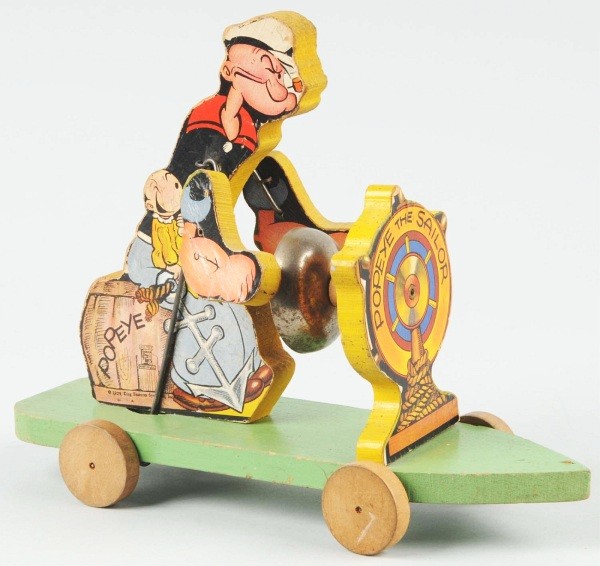 Fisher Price No. 703 Popeye the Sailor Toy.: Paper on wood. Marked "1929 King Features Syndicate". Sweet Pea is sitting on Popeye's lap. When in operation, Popeye's hands hit bell. Some crazing to paper and edge wear throughout. 11 - 1/2" L. (Ve