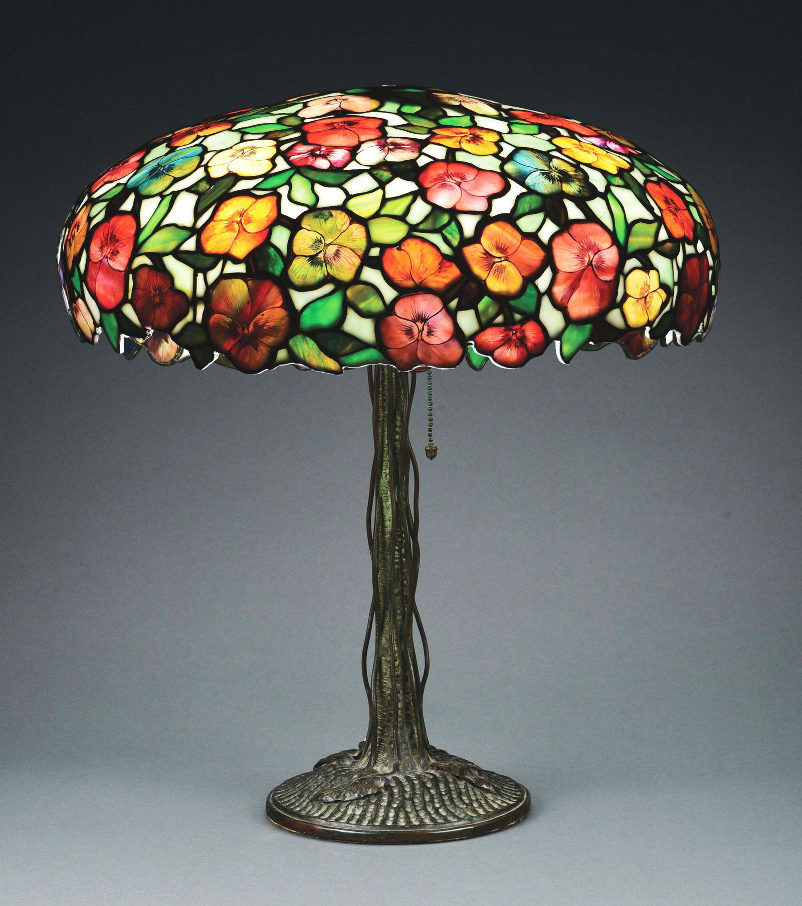 JOHN MORGAN AND SONS PANSY LEADED GLASS LAMP.: An absolutely gorgeous example of the rare and coveted Pansy lamp by John Morgan and Sons, New York, c. 1905. The 18” diameter leaded glass shade features a background of streaked green and whit