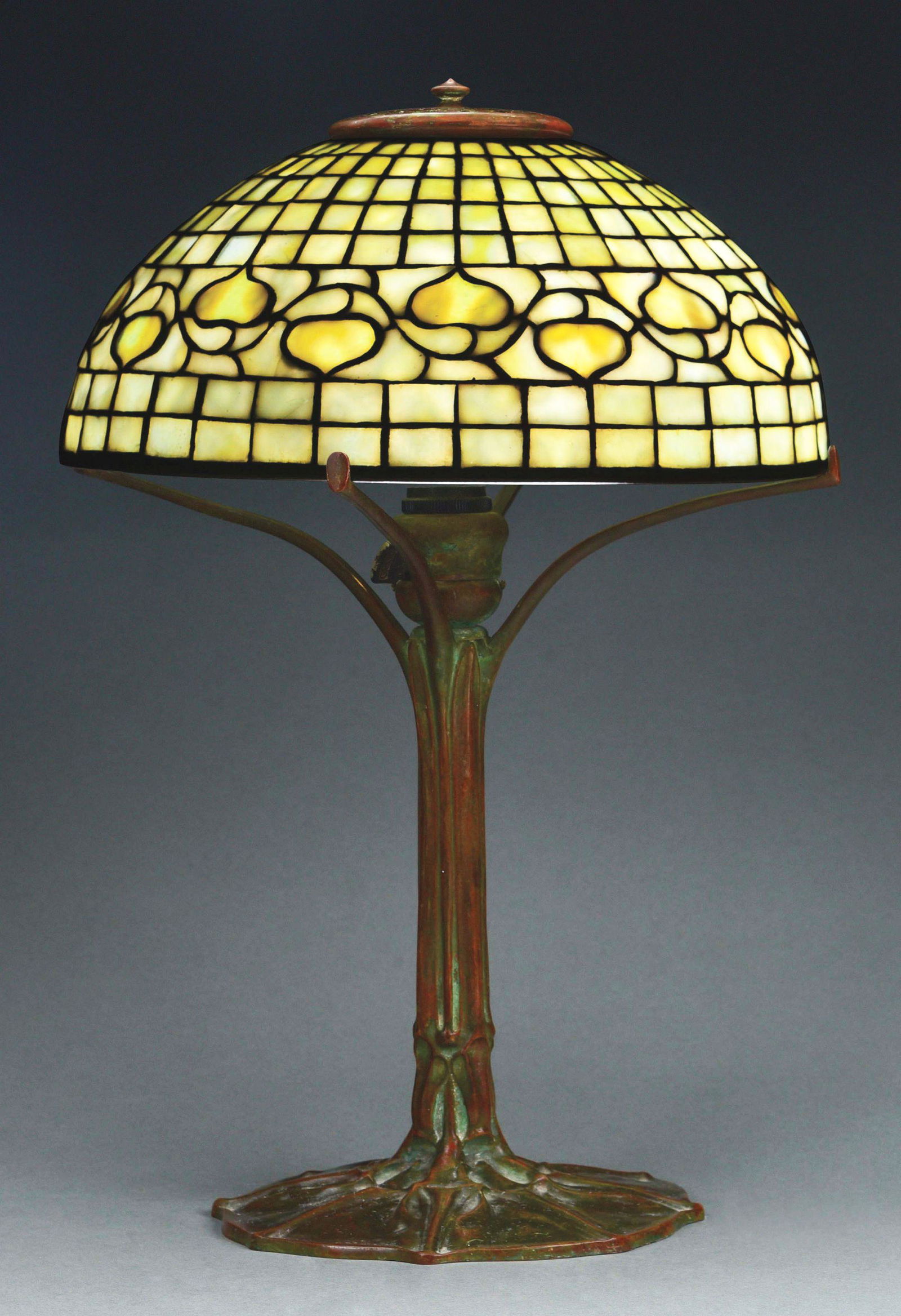 TIFFANY STUDIOS ACORN TABLE LAMP.: Tiffany Studios cast bronze and leaded stained glass Acorn table lamp decorated with leaded stained glass and patinated Acorn pattern shade, with a belt of yellow-white mottled and stippled glass acor