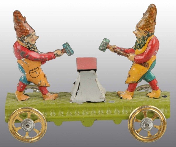 Tin Litho Gnomes Hammering Anvil Penny Toy.: German. On platform with gold-wash wheels. Depicts two gnomes holding hammers and simulating hitting a blacksmith's anvil. Some litho loss to figures. 3 - 1/2" L. (Very Good - Excellent).