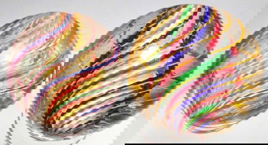 Lot of 2: 3-Stage Swirl Marbles.: One marble has yellow and orange solid core surrounded by a middle core of white latticino with outer bands of alternating pink/white/blue and pink/white/green. Other has a white solid core with middl