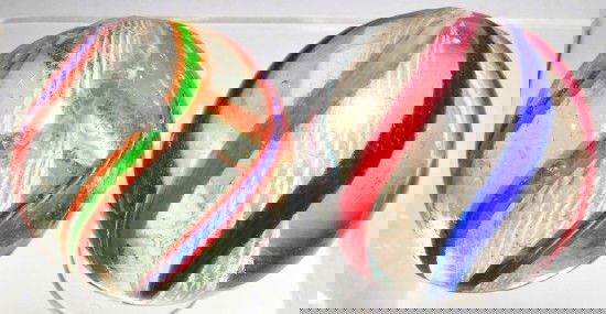 Lot of 2: Large Latticino Swirl Marbles.: One a white latticino with outer bands of blue/white, red/white and green/white. Other a white latticino with outer alternating bands of green/orange and blue/orange. Size: Largest: 2" Dia.