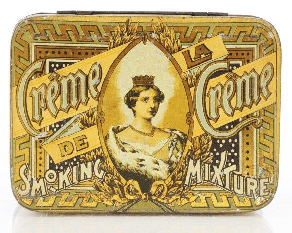 Creme de la Creme Smoking Mixture Tin.: Tobacco manufactured by J.M. Fortier in Montreal, Canada. Beautiful image of Queen on a brightly colored tin containing metallic gold. Size: 5" L.