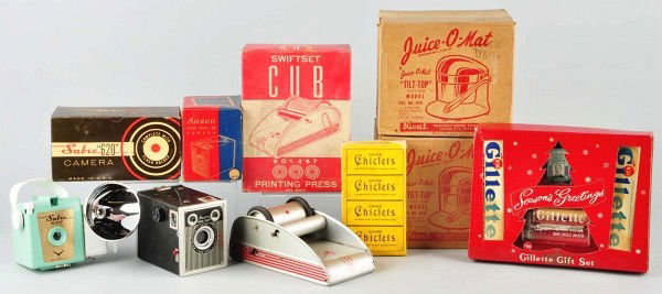 Lot of 7: Old Drug Store Stock Items.: Circa 1950s. Includes unopened box of Chiclets Gum, Gillette Shaving advertising piece, one small printing press, two juicers sealed in boxes, and two cameras. Boxes have some creasing and tearing. Si