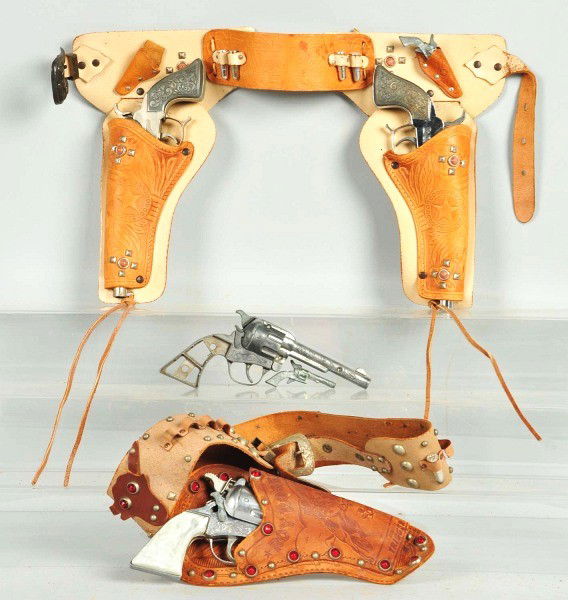 Lot of 2: Roy Rogers Gun & Holster Sets.: Includes one double set with two Roy Rogers Classy Products guns with finish wear, one gun firing improperly, and heavy wear to holster and belt. The other set was a double set at one time but the lef