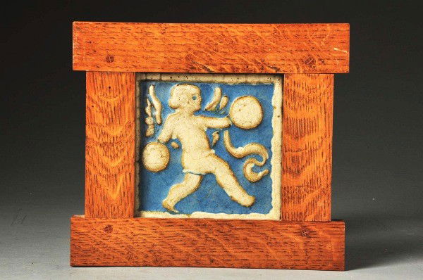 Grueby Faience 2-Color Tile.: Red clay depicting boy with symbols. In a pinned, contemporary oak frame. Size: Framed: 10 - 1/4" x 9 - 3/4".