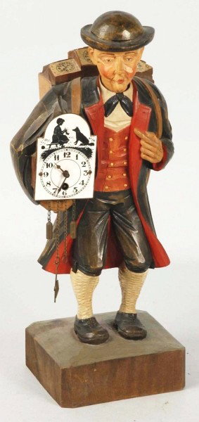 Hand Carved German Whistler & Clock.: Working. Depicting a man carrying clocks on his back. When wound, man whistles while his head turns from side to side. Includes original key. Size: 13 - 1/4" T.
