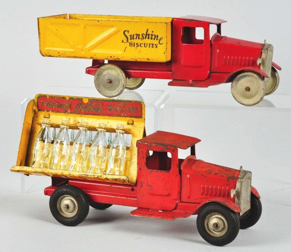 Lot of 2: Pressed Steel Metalcraft Truck Toys.: American. Includes one Coca-Cola truck with ten miniature glass bottles and black rubber tires. Also includes one Sunshine Biscuits dump truck with tin wheels. Both toys with paint chipping and loss, 