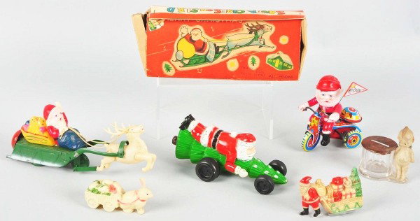 Lot of 6: Santa Claus, Holiday, & Kewpie Items.: Includes two pre-war celluloid rattles, one celluloid and tin Santa in sleigh with original box, one later plastic Santa riding tree, one later plastic Santa riding tricycle, and one glass Kewpie bank