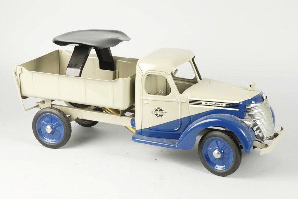 Pressed Steel Buddy L Sit and Ride Dump Truck.: Description American. Circa 1938. International front cab with dual tone slant paint, dump body with automatic opening tail gate. Maintains its original seat but missing its pull handle. Professional 