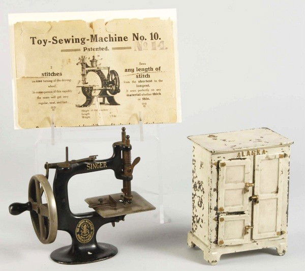 Lot of 2: Cast Iron Toy Items.: Description American. Includes one Arcade Alaska Ice Box and one Singer Sewing Machine. Sewing machine comes with original instruction sheet. Some paint loss and wear to ice box. Condition (Very Good)
