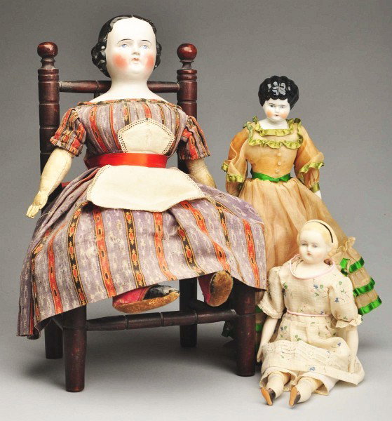 Lot of 3 Dolls & 1 Chair.: 1890s china shoulder head, original cloth body and china lower limbs, nicely dressed; M. Brouse parian reproduction doll; 1860s German china head (repaired nose), black molded hair (some small paint c