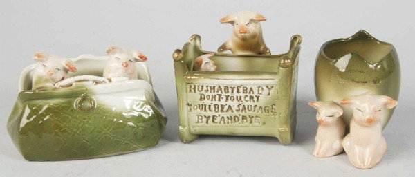 Lot of 3: German Porcelain Pig Novelties.: Two pigs in travelling bag, pig with cradle "Hush Baby Don't You Cry, You'll be a Sausage Bye and Bye," two pigs with an egg. Size: Laregest: 3" T.