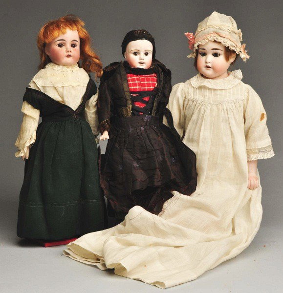 Lot of 3: German Bisque Dolls.: Two are shoulder heads with glass eyes, open mouths, and mohair wigs on kid bodies with bisque lower arms, wearing vintage clothing (doll in jumper has repaired face). One is an early shoulder head wi