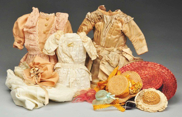 Lot of Vintage Doll Clothes & Hats.: Antique silk dress (some melting) for a larger doll, vintage eyelet dress with two lingerie pins, newer tan silk dress and hat, large white cotton baby dress, red straw hat, yellow straw hat with ribb