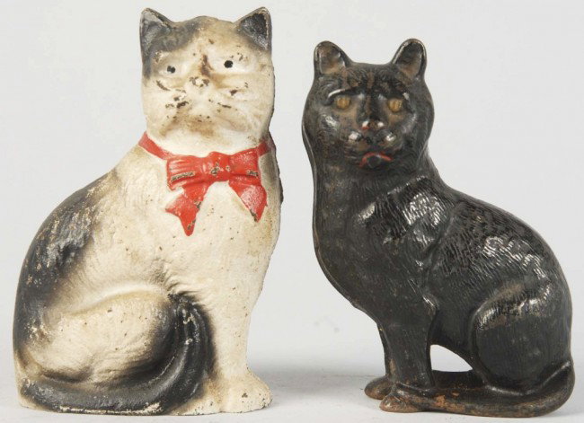 Lot of 2: Cast Iron Cat Still Banks.: Includes one Cat with Bow made by John Wright and one Arcade Seated Cat with Soft Hair circa 1910 to 1929. Some wear overall. Size: Largest: 4 - 1/2" T. Condition: (Very Good).