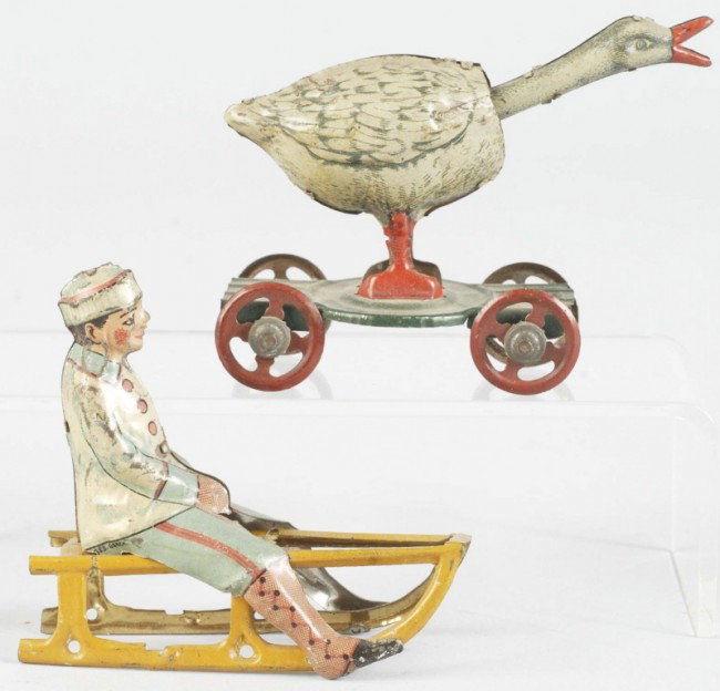 Lot of 2: Tin Litho Character Penny Toys.: German. Includes one goose on platform with movable head and one boy on sled with some litho loss. Size: Largest: 2 - 5/8" T. Condition: (Very Good).