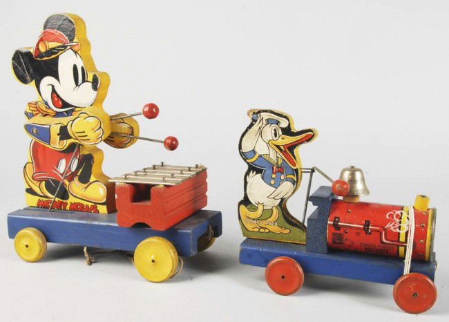 Lot of 2: Fisher Price Walt Disney Pull Toys.: American. Includes one Mickey Mouse No. 798 Xylophone and one No. 465 Donald Duck Choo-Choo. Some creasing and slight paper loss to both toys. Size: Largest: 11" T. Condition: (Very Good).