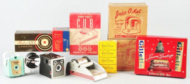 Lot of 7: Old Drug Store Stock Items.: Circa 1950s. Includes unopened box of Chiclets Gum, Gillette Shaving advertising piece, one small printing press, two juicers sealed in boxes, and two cameras. Boxes have some creasing and tearing. Si