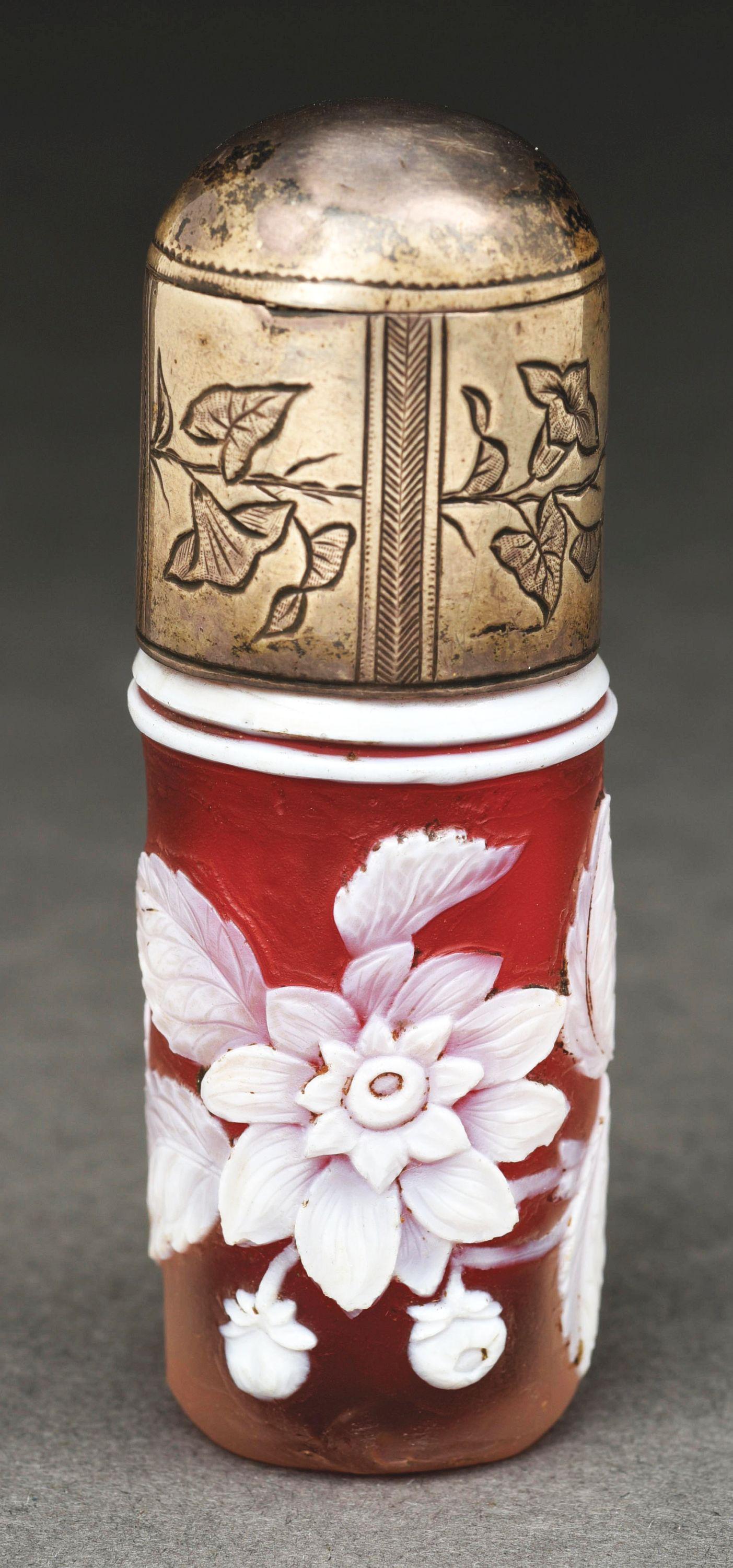 WEBB CAMEO PERFUME.: Small cameo perfume attributed to Thomas Webb and Sons. White flowers and leaves on a red background with a silver cap engraved with morning glories. Minor tarnish to the cap from age and a couple sma