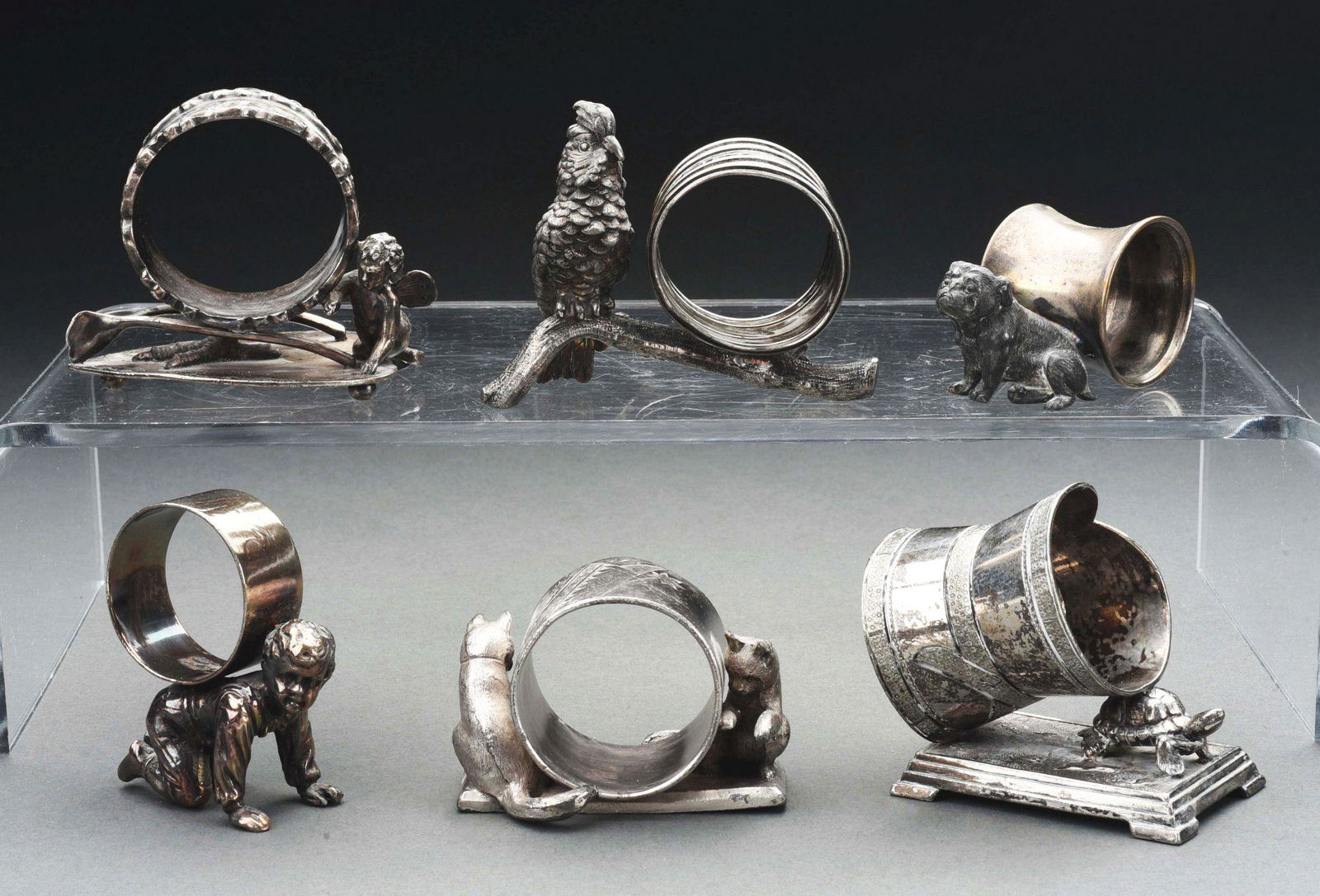 LOT OF 6: VICTORIAN FIGURAL NAPKIN RINGS.: Lot of six Victorian figural napkin rings consists of: first, a napkin ring with angel at base and wishbone, 2 - 1/2"; second, a boy crawling on hands and knees, 2 - 3/4"; third, a large parrot on bra